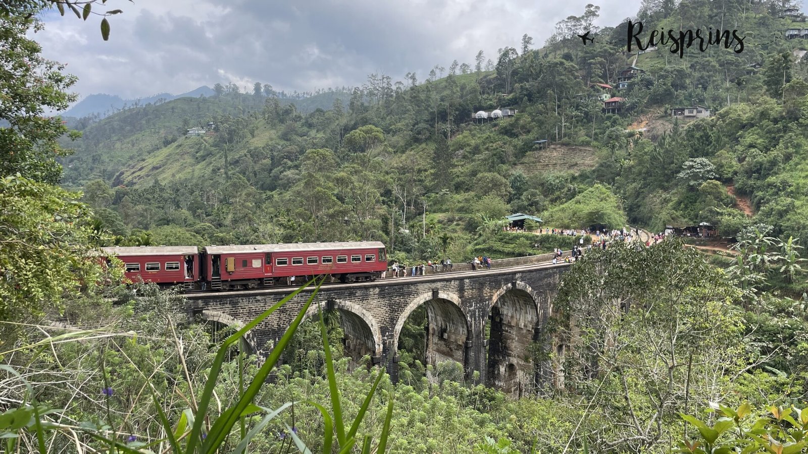 Uitzicht van ver af op de Nine Arches Bridge in Ella in Sri Lanka met passerende trein